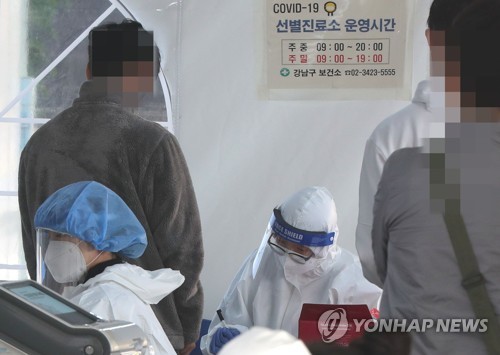 Medical workers carry out new coronavirus tests at a makeshift clinic in southern Seoul on Oct. 20, 2020. (Yonhap)