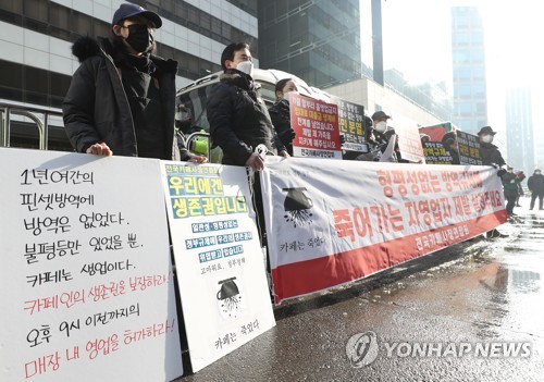 Member of a cafe owners' association demand the lifting of COVID-19 business restrictions during a rally outside the ruling Democratic Party's headquarters in Seoul on Jan. 13, 2021. (Yonhap)