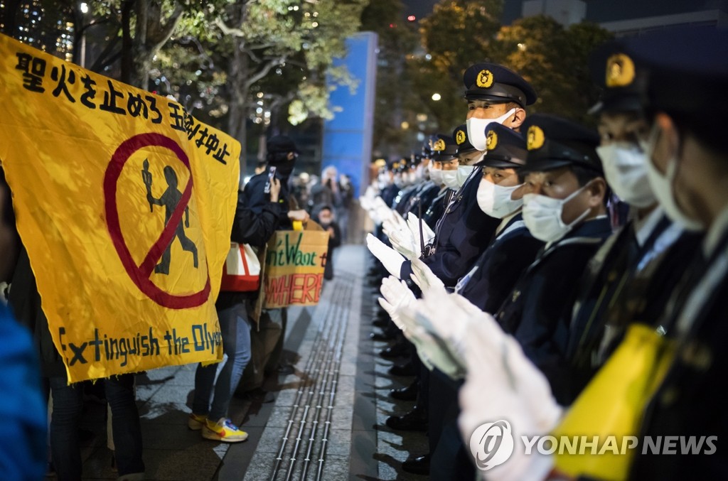 (도쿄 AP=연합뉴스) 2021년 3월 25일 일본 도쿄 시내에서 경찰이 올림픽 개최에 반대하는 시위대를 마주하고 있다.