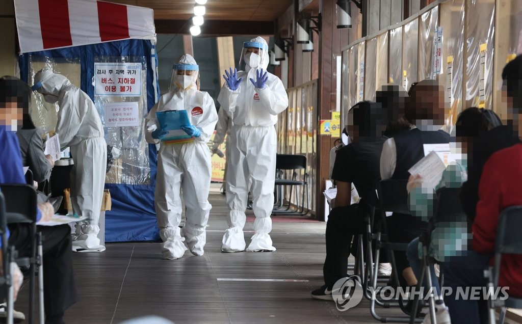 Health workers in protective suits guide citizens at a makeshift virus testing clinic in Seoul on April 22, 2021. (Yonhap)
