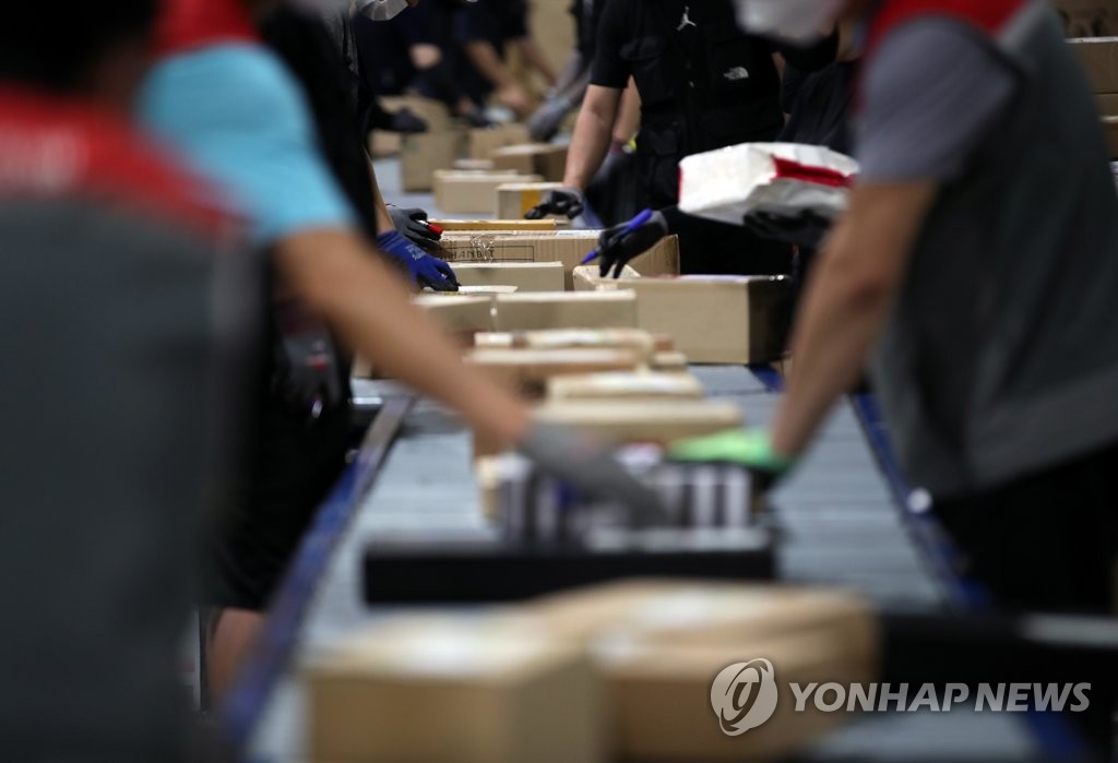 This June 18, 2021, file photo shows workers sorting parcels at a distribution center in Seoul. (Yonhap)