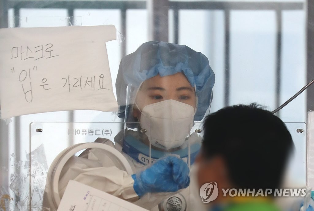 A medical worker collects a specimen from a man for a coronavirus test at a makeshift testing center near Seoul Station in central Seoul on June 22, 2021. (Yonhap)