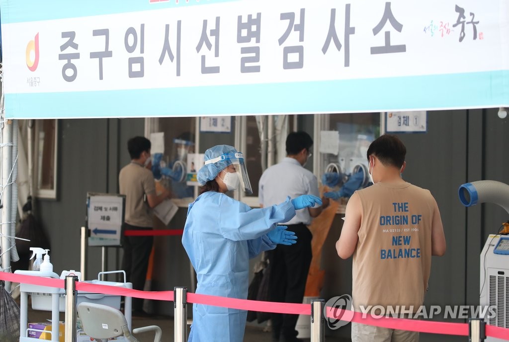 A medical worker collects a specimen from a man at a makeshift testing center near Seoul Station in central Seoul on June 23, 2021. (Yonhap) 