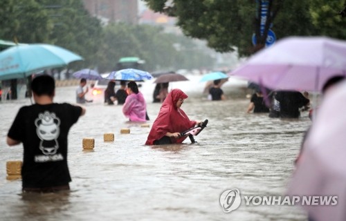 물에 잠긴 도로를 걸어가는 중국 정저우 주민들