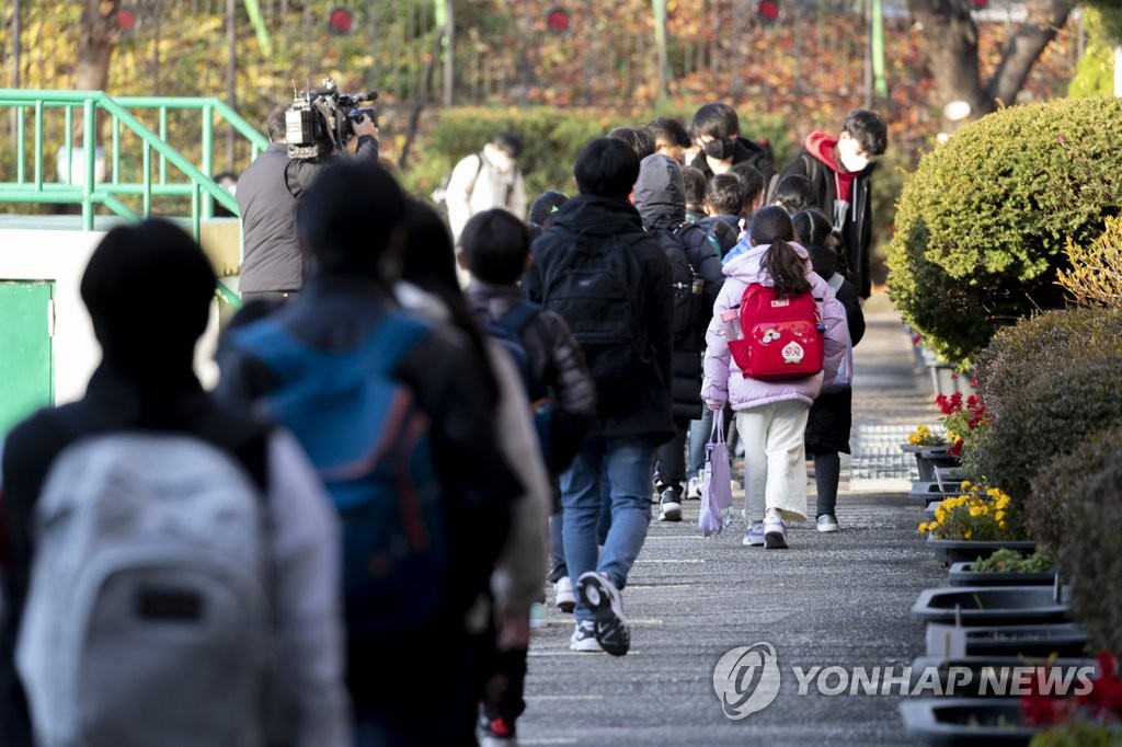 This Nov. 22, 2021, file photo shows students walking to an elementary school in the southeastern city of Changwon to attend in-person school classes. (Pool photo) (Yonhap)