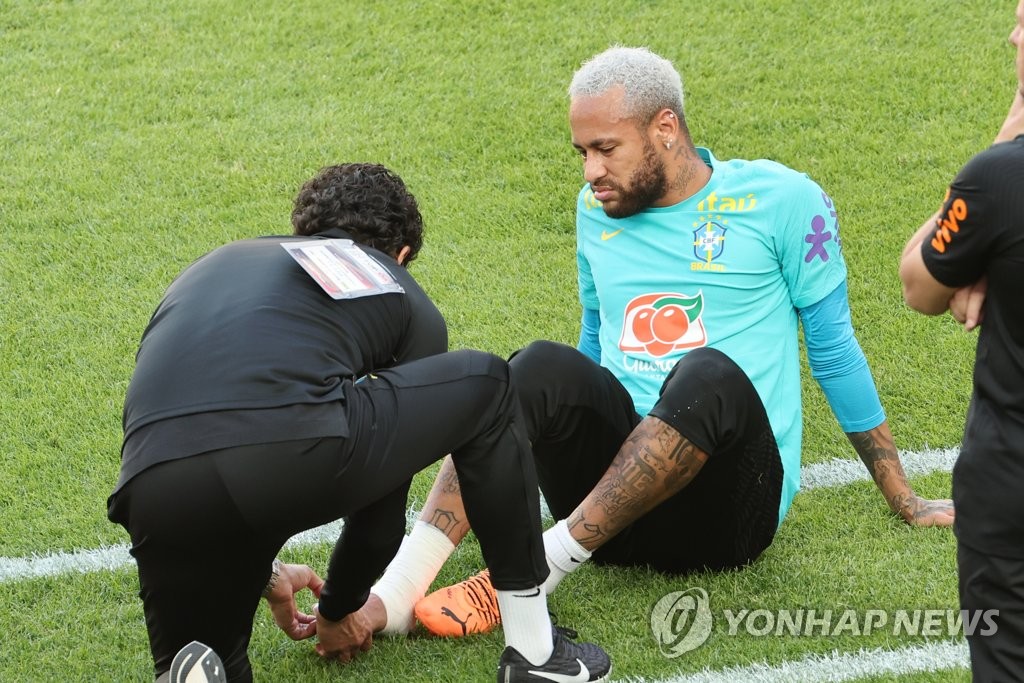 Brazilian forward Neymar (R) is attended to by a team trainer after sustaining an apparent right foot injury during a training session at Seoul World Cup Stadium in Seoul on June 1, 2022, the eve of a friendly match against South Korea. (Yonhap)