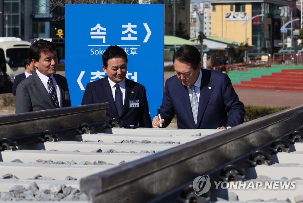 El presidente surcoreano, Yoon Suk-yeol (dcha.), firma en una traviesa de una nueva vía férrea, que unirá las ciudades norteñas de Chuncheon y Sokcho, en la provincia de Gangwon, durante una ceremonia de inicio de construcción, celebrada, el 18 de octubre de 2022, en una plaza de Sokcho, a 158 kilómetros al noreste de Seúl.