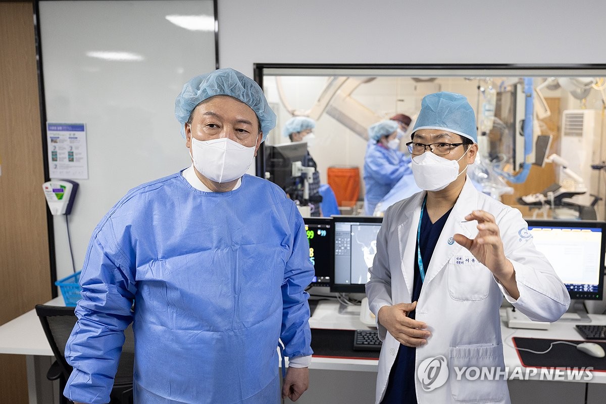 President Yoon Suk Yeol (L) listens to the chief of the cardiovascular center at Hankook General Hospital in Cheongju, 112 kilometers southeast of Seoul, on March 26, 2024, in this photo provided by his office. (PHOTO NOT FOR SALE) (Yonhap)