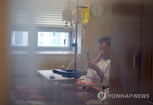 Saenuri Party Chairman Lee Jung-hyun, admitted to a Seoul hospital after a weeklong hunger strike, looks at his cell phone at his hospital room on Oct. 3, 2016. (Yonhap)
