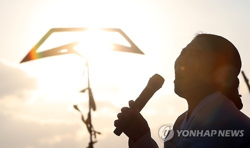 A South Korean artist performs a song at Paengmok Harbor on Jan. 9, 2017, to wish for the missing victims' return on the 1,000th day since the ferry Sewol sank. (Yonhap)