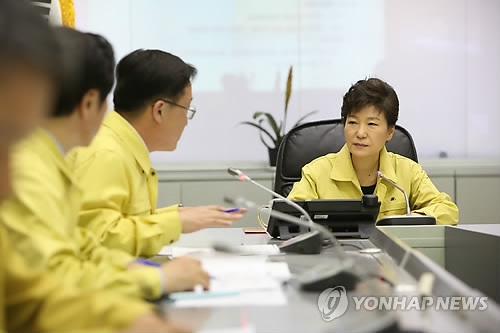 This photo, provided by the presidential office Cheong Wa Dae, shows President Park Geun-hye (R) being briefed on the sinking of the ferry Sewol at the government disaster control agency in Seoul on April 16, 2014. (Yonhap)