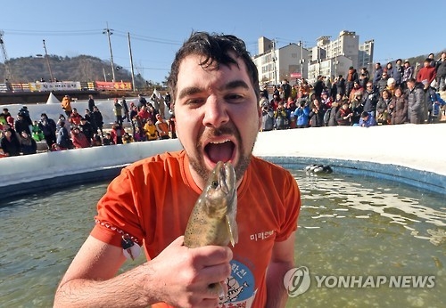 A foreigner holds up a mountain trout he caught with his bare hands during a festival in Hwacheon on Jan. 15, 2017. (Yonhap)