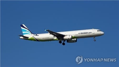 This undated file photo shows an A321-200 jet operated by Air Busan in flight near an airport. (Yonhap)