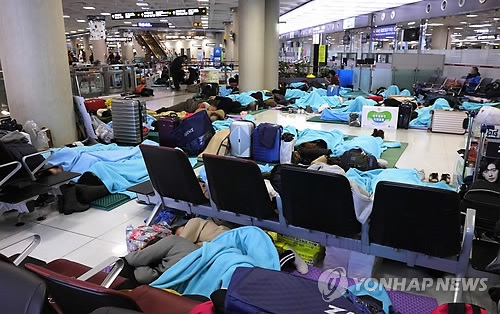 Tourists sleep in the lobby of Jeju International Airport on the southern resort island of Jeju on Jan. 12, 2018, as heavy snow and strong winds caused hundreds of flight cancellations and delays the previous day. (Yonhap)