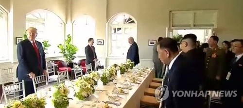 This photo captured from The Straits Times' website shows Trump and Kim standing across a table before starting their working lunch at the Capella Hotel in Singapore on June 12, 2018. (Yonhap)