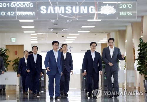 Finance Minister Kim Dong-yeon (2nd from R) talks with Samsung Electronics Vice Chairman Lee Jae-yong (R) while moving into a room for talks at the tech giant's chipmaking line in Pyeongtaek, south of Seoul, on Aug. 6, 2018. (Yonhap)