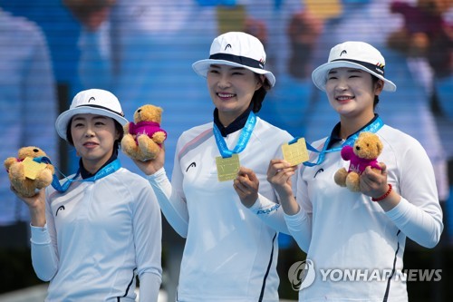 In this EPA file photo from July 22, 2018, South Korean archers Chang Hye-jin, Jung Dasomi and Kang Chae-young (from L to R) hold up their gold medals after winning the women's recurve team title over Britain at the Archery World Cup in Berlin. (Yonhap)