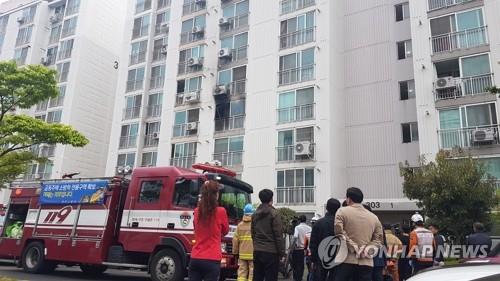 Residents of an apartment building in Jinju, South Gyeongsang Province, and firefighters watch the scene of an arson and murders on April 17, 2019. (Yonhap)