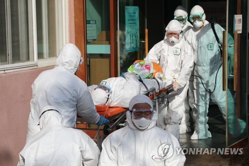 Medical workers transfer a suspected coronavirus patient from Daenam Hospital in Cheongdo, 320 kilometers southeast of Seoul, to another hospital on Feb. 21, 2020. Of about 600 patients and medical staff at the hospital, 16 tested positive for COVID-19, health authorities said. (Yonhap)