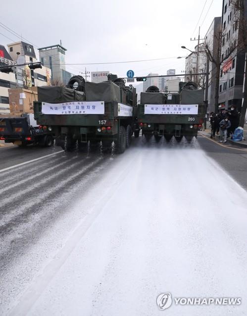 Military vehicles from the Capital Defense Command spray disinfectant on a road in Seoul on March 4, 2020, as part of preventive measures against the spread of the COVID-19 coronavirus. (Yonhap) 