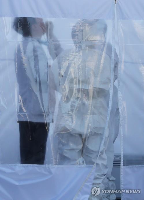 Medical workers in protective gear take a sample from a man at Jesaeng Hospital in Seongnam, south of Seoul, on March 6, 2020, after eight cases of new coronavirus infections were confirmed. (Yonhap)