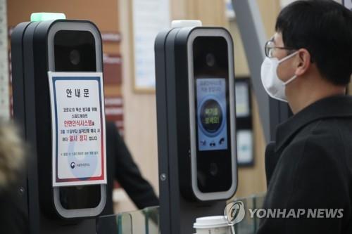 A government employee enters a gate of the government complex in Seoul on March 11, 2020, with a face mask on, as the operation of a facial recognition system to enter the complex has been suspended amid the spread of the new coronavirus. (Yonhap)