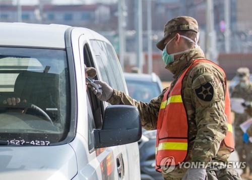 A military guard checks the temperature of a driver at the entrance to the U.S. Army Garrison Humphreys compound in Pyeongtaek, 70 kilometers south of Seoul, on Feb. 28, 2020, to prevent spread of the novel coronavirus, in this photo provided by United States Forces Korea. (PHOTO NOT FOR SALE) (Yonhap)