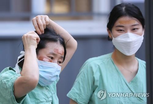 Medical staffers use bandages to cover wounds on their faces caused by wearing protective goggles for long hours while treating coronavirus patients at Dongsan Hospital in Daegu, 300 kilometers southeast of Seoul, on March 4, 2020. (Yonhap)
