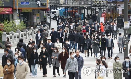 People wearing masks walk in Seoul's Jongno Ward on April 20, 2020, as South Korea began to partially ease social distancing measures the same day amid the coronavirus pandemic. Under the measures, churches, bars, gyms and cram schools are allowed to resume business. (Yonhap)