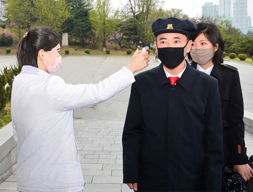 This photo, captured from the website of North Korean propaganda outlet Naenara on April 20, 2020, shows North Korean students getting their temperatures checked before going into class. (Yonhap) 