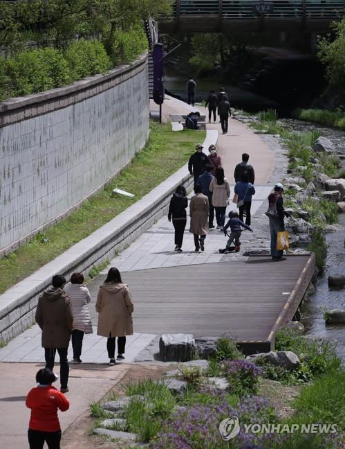 People stroll on a trail along the Cheonggye Stream in Seoul's Jung Ward on April 21, 2020, one day after South Korea began to partly soften its social distancing guidelines amid the coronavirus pandemic. (Yonhap)