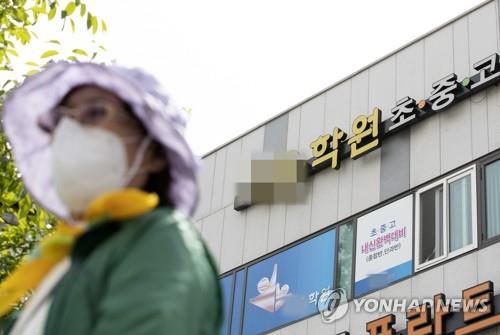 This file photo shows a masked citizen passing by a private academy in Incheon, where a coronavirus-infected instructor taught students. (Yonhap)