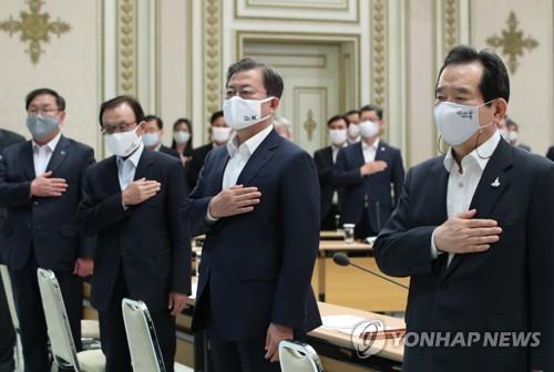 President Moon Jae-in (C), Prime Minister Chung Sye-kyun (R) and other politicians place their hands on their hearts while facing the national flag during an annual national fiscal strategy meeting at the presidential office Cheong Wa Dae in Seoul on May 25, 2020. (Yonhap)