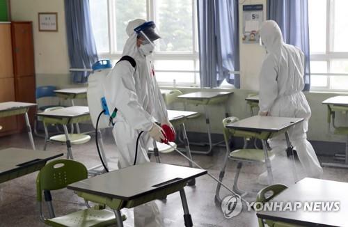 Health care officials disinfect a high school in the southeastern port city of Busan on May 30, 2020, after a third grader was confirmed to have contracted the new coronavirus a day earlier. (Yonhap)