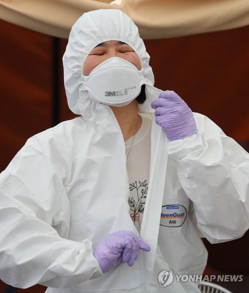 A medical worker takes off her protective gear after finishing a shift at an outdoor clinic for coronavirus tests in Seoul on June 10, 2020, amid a heat wave. (Yonhap)