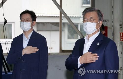 South Gyeongsang Province Gov. Kim Kyoung-soo (L) and President Moon Jae-in pledge allegiance to the national flag in an industrial event in Changwon, South Gyeongsang Province, on Sept. 17, 2020. (Yonhap)