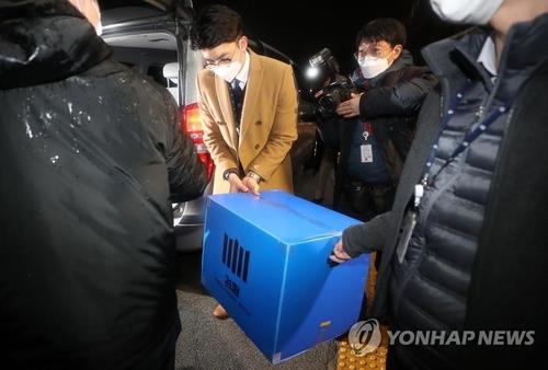 In this file photo, investigators carry a box of documents out of the Ministry of Justice after raiding the ministry in connection with an investigation into an allegedly illegal overseas travel ban on Kim Hak-ui, a former vice justice minister, in Gwacheon, south of Seoul, on Jan. 21, 2021. (Yonhap)