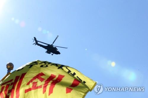 An Apache attack helicopter engages in live-fire training as a group of residents stages a rally in front of an Apache helicopter firing range in Pohang, North Gyeongsang Province, southeastern South Korea, on Feb. 4, 2021, with the residents calling for the closure of the live-fire firing site of the U.S. Forces Korea. (Yonhap)
