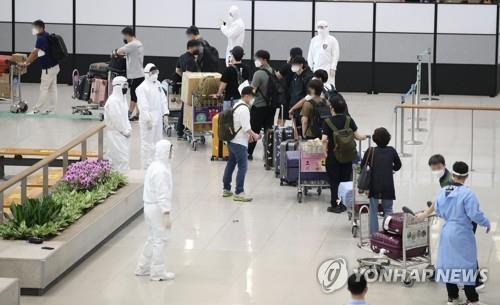 In this July 13, 2021, file photo, South Korean residents and diplomats from India are guided by quarantine officials upon their arrival at Incheon International Airport, west of Seoul, amid the fourth wave of the COVID-19 pandemic. (Yonhap)