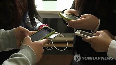 In this image provided by Yonhap News TV, teenagers use smartphones. (PHOTO NOT FOR SALE) (Yonhap)