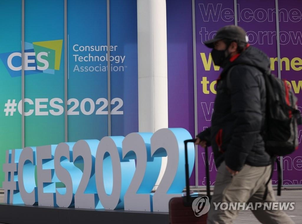 A man passes by a wall decorated by signs of the Consumer Electronics Show, set to run from Jan. 5-7 in Las Vegas, on Jan. 3, 2022. (Yonhap)