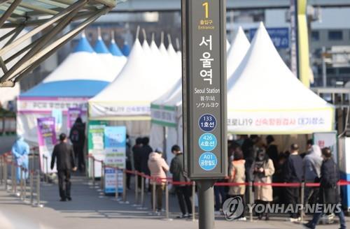 People stand in line to take coronavirus tests at a screening clinic in front of Seoul Station on March 22, 2022. South Korea's new COVID-19 cases spiked to over 350,000 on the day, adding to concerns that infections could spike again as the accumulated caseload nears 10 million. (Yonhap)