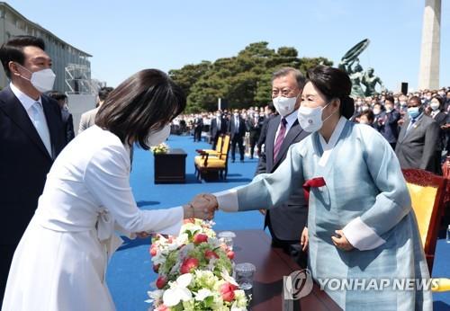 In this file photo, South Korea's first lady Kim Keon-hee (L) shakes hands with Kim Jung-sook (R), the wife of former President Moon Jae-in, at the inauguration ceremony for President Yoon Suk-yeol held at the National Assembly in Seoul on May 10, 2022. (Yonhap)