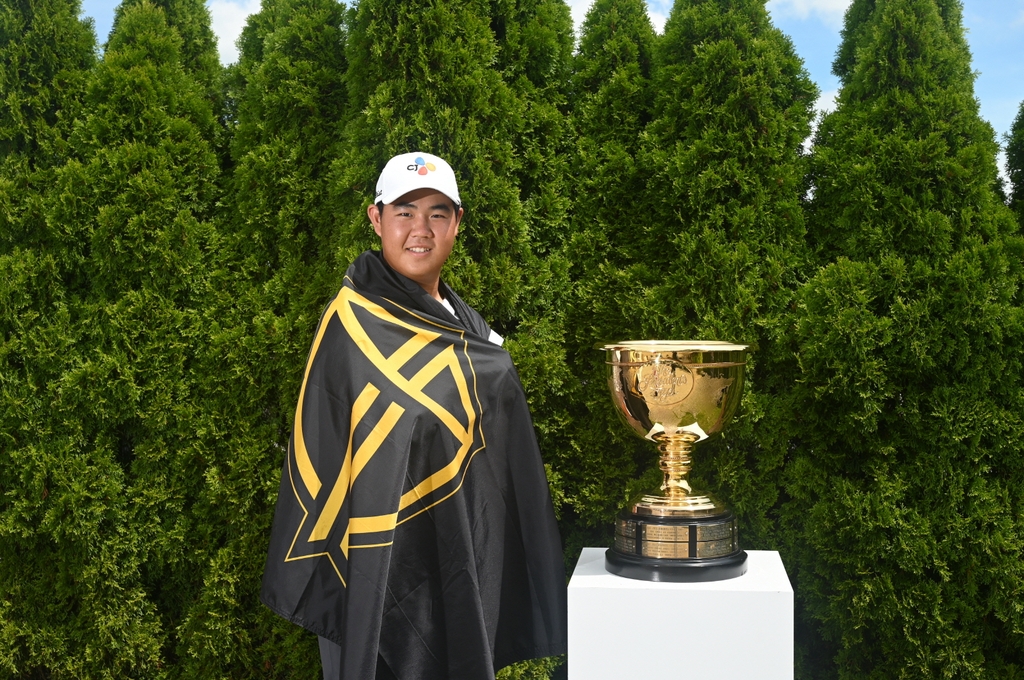 In this photo provided by the PGA Tour on Aug. 22, 2022, South Korean golfer Kim Joo-hyung poses next to the winner's trophy while draped in a flag bearing the logo of the International Team. (PHOTO NOT FOR SALE) (Yonhap)