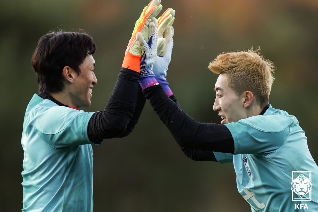 South Korean goalkeepers Kim Seung-gyu (L) and Jo Hyeon-woo high-five each other during a training session with the men's national football team at the National Football Center in Paju, Gyeonggi Province, on Nov. 4, 2022, in this photo provided by the Korea Football Association. (PHOTO NOT FOR SALE) (Yonhap)