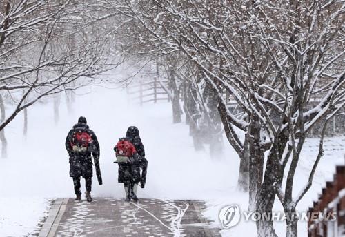 Workers blow away snow in the county of Yanggu on Dec. 15, 2022. (Yonhap)