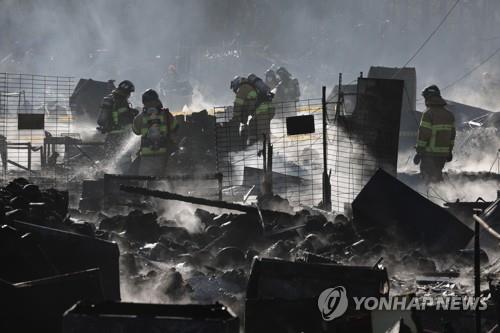 Firefighters examine gutted makeshift buildings in Guryong Village, the last remaining slum in Seoul, in the capital's Gangnam Ward on Jan. 20, 2023. (Yonhap)