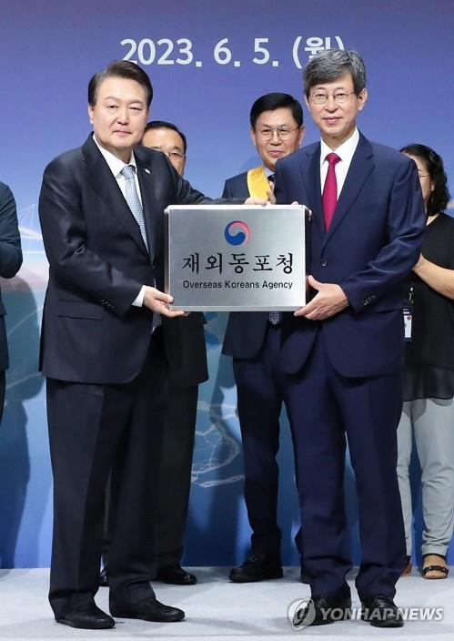President Yoon Suk Yeol (L) poses for a photo with Lee Key-cheol, the inaugural head of the newly launched Overseas Koreans Agency, after presenting him with the agency's signboard during its opening ceremony in Incheon, 27 kilometers west of Seoul, on June 5, 2023. (Pool photo) (Yonhap)