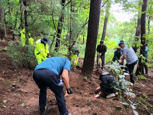 Esta foto proporcionada por la Agencia de Policía Provincial de Gyeongnam muestra al personal policial buscando en una montaña el cuerpo de un bebé recién nacido.  Una pareja fue arrestada el 2 de julio de 2023, acusada de estrangular a su bebé recién nacido y abandonar su cuerpo en la ciudad sureña de Geoje.  (Yonhap) (FOTO NO A LA VENTA)