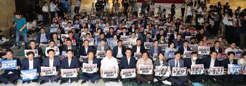 Lee Jae-myung (sexto de izquierda a derecha, primera fila), líder del principal Partido Democrático de la oposición, y otros legisladores del partido cantan consignas durante un mitin en la Asamblea Nacional en Seúl el 6 de julio de 2023, mientras lanzan una vigilia nocturna contra Japón. planear descargar agua radiactiva tratada de los reactores nucleares paralizados en Fukushima en el océano.  (Yonhap)